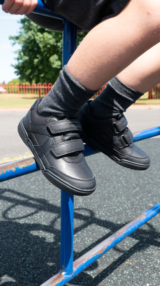 Boys Black Geox School shoes, being worn with grey socks on a childrens climbing frame