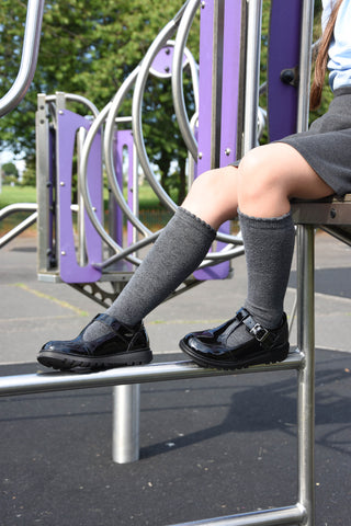 Patent black hush puppies t-bar school shoes on a child in a play area